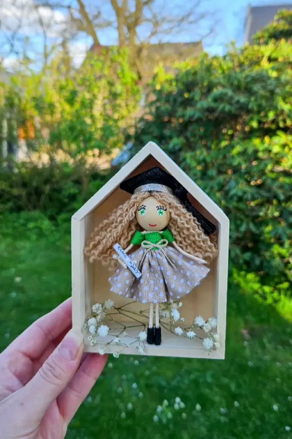 Doll in a little wooden house, held outdoors