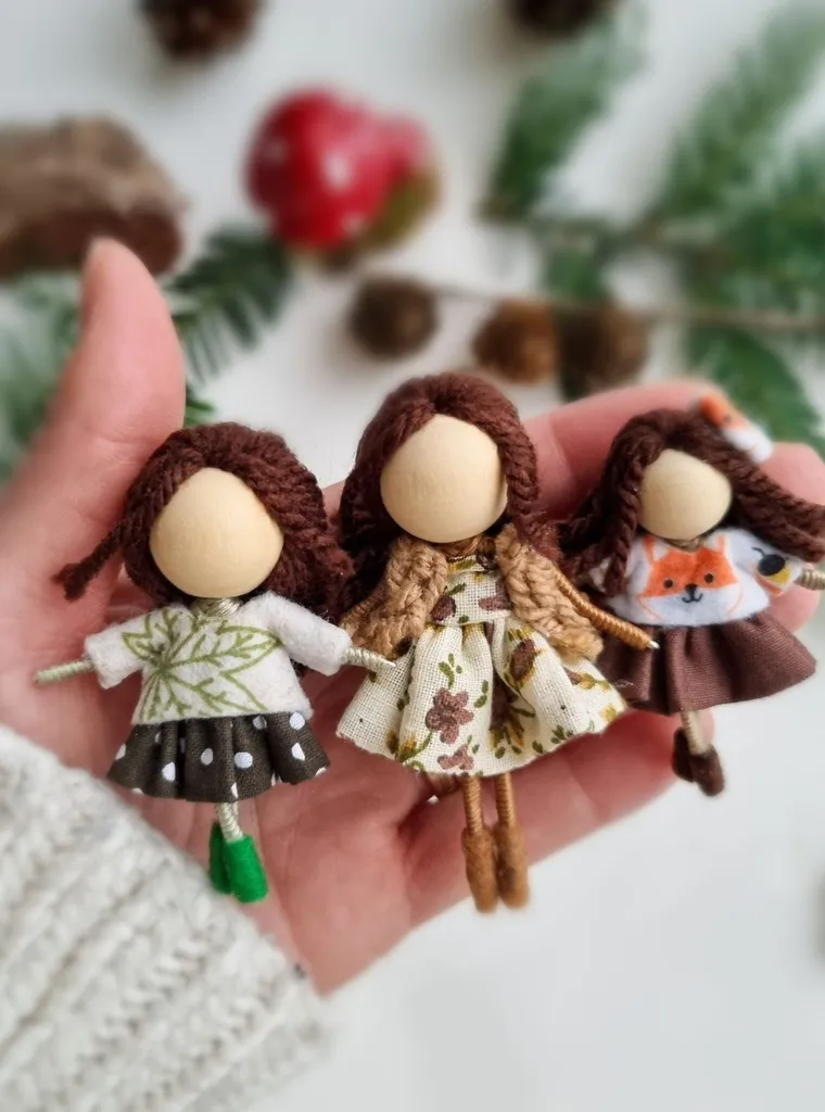 Three handmade dolls in autumn dresses in the maker's hand