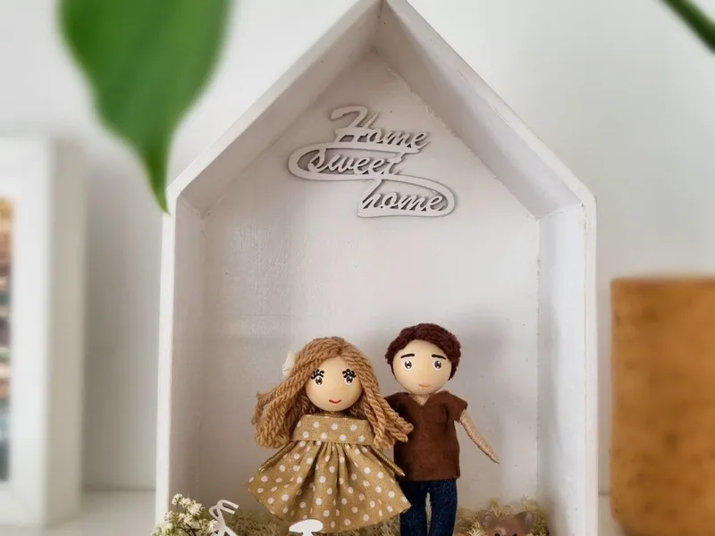 Couple dolls in a 'Home sweet home' house frame