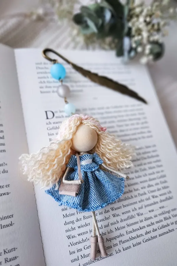 Bookmark doll with a denim dress on an open book
