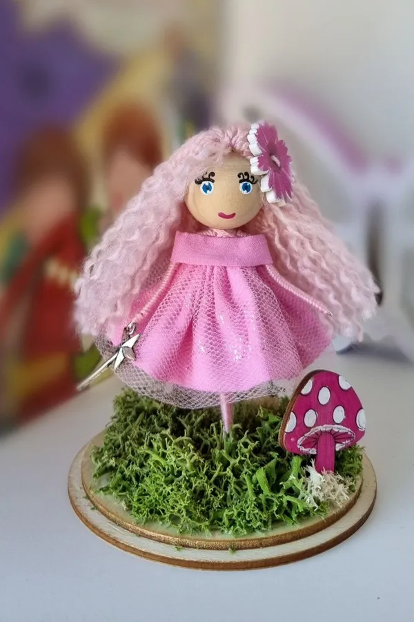Pink-haired doll on a moss base with a mushroom