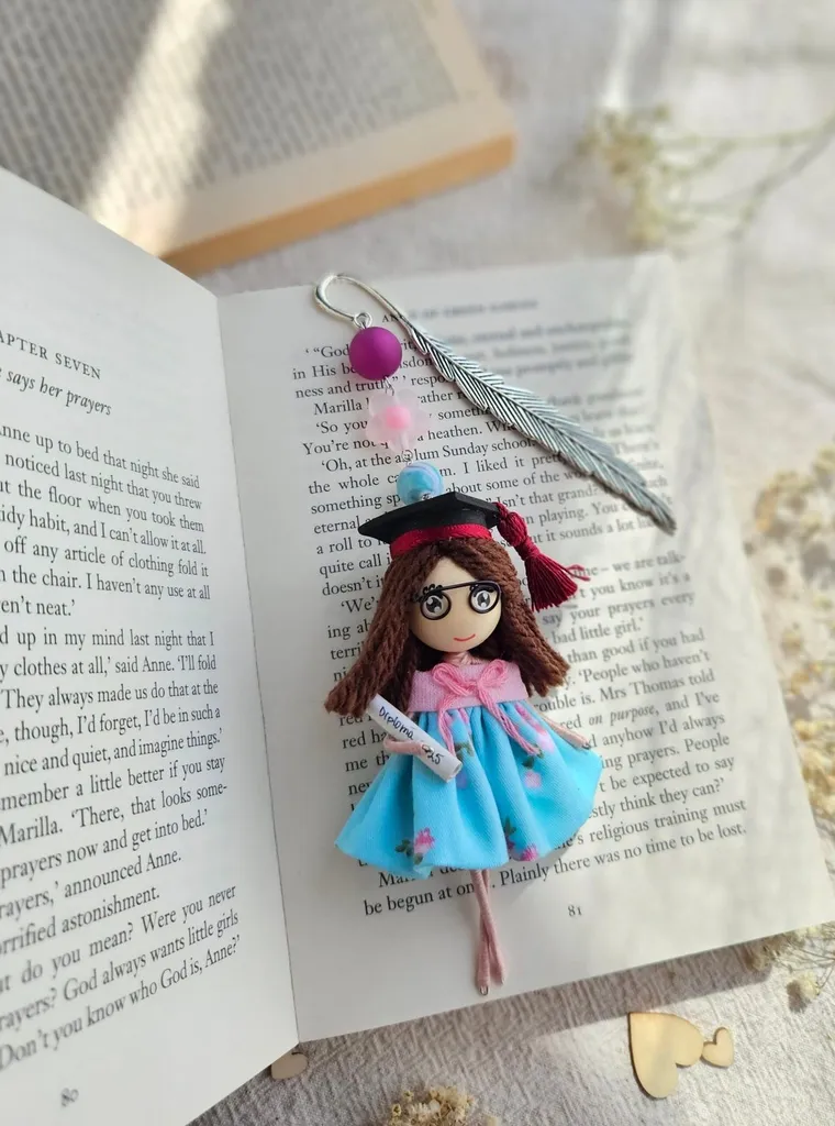 Bookmark doll with a feather charm on a book